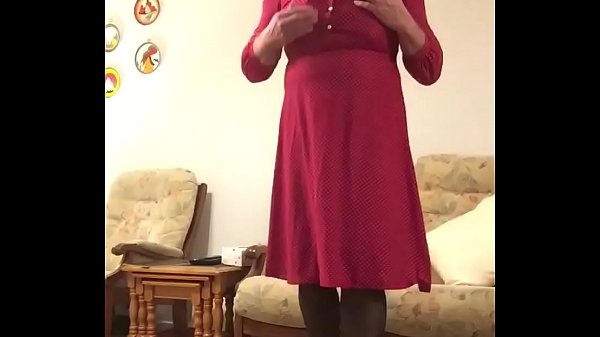 Johanna poses in red dress and white heels in lounge. Using Rimba Electro Stim attached to cock. 