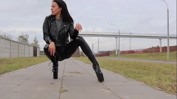 Brunette wearing tight_leather_leggingshigh heels and_a leather biker_jacket