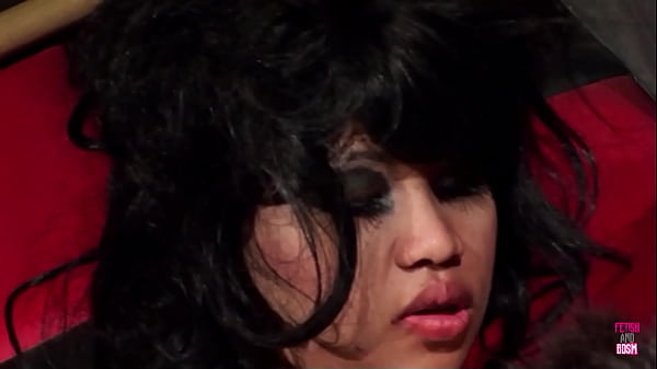 A pair of asian descent including a brunette individual engages in sexual activity while wearing latex attire and restraints culminating in a facial climax inside a bdsm dungeon
