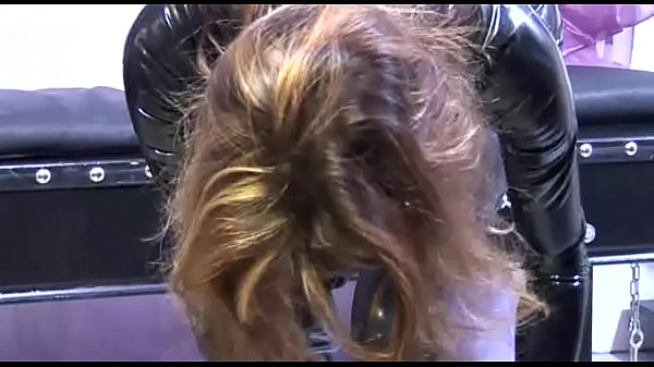 A sexy slave with a latex dress is kept in chains