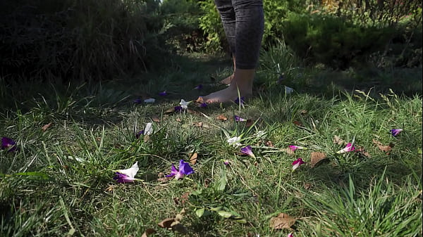 Sexy feet with long toes crushing flowers outdoors 
