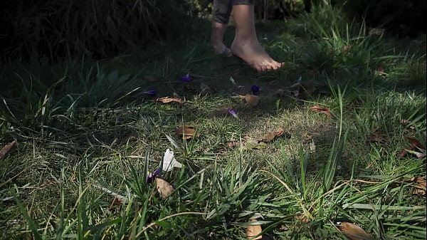 Sexy feet with long toes crushing flowers outdoors 