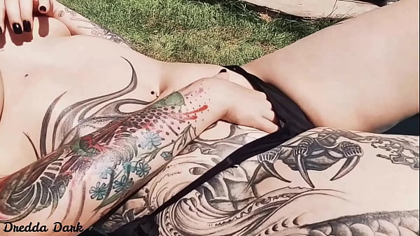Tattooed horny brunette with big boobs sunbathing in the yard and rubbing sunscreen on her tits