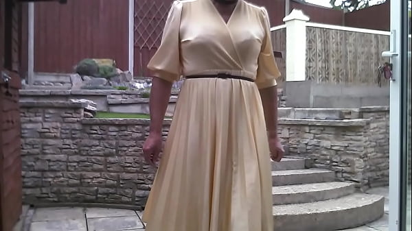 Transvestite poses outside wearing yellow dress 