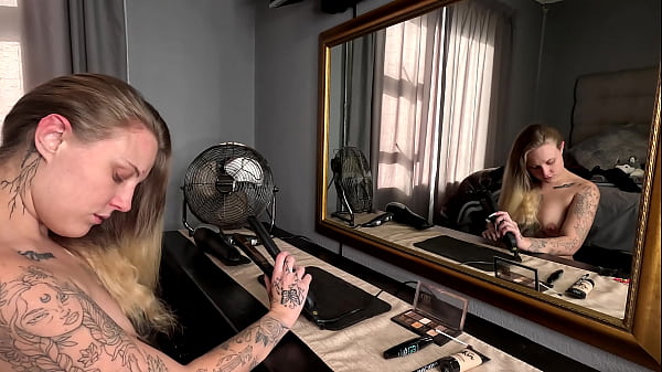 Sexy tattooed blonde girl doing her hair and makeup naked 