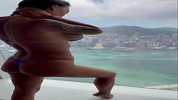 Monika fox in purple bikini swims in pool & poses by window against background of city free